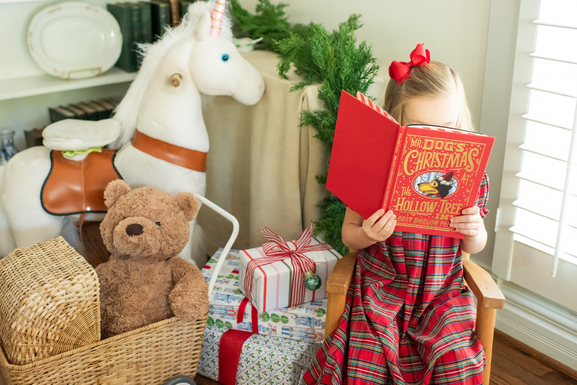 Girl Reading Christmas Book next to wrapped gifts