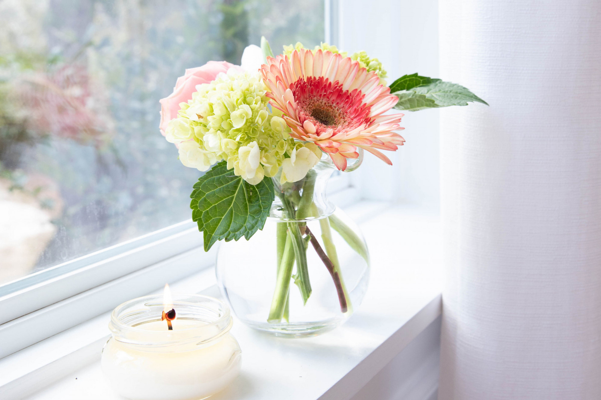Sympathy flowers on windowsill with a candle